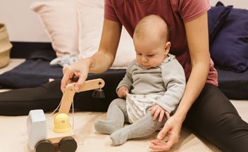 bebé jugando en el suelo con una profesional de Yummy Mummy